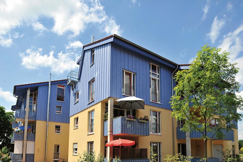 Außenansicht eines mehrstöckigen Wohnhauses mit farbenfroher Fassade vor blauem Himmel
