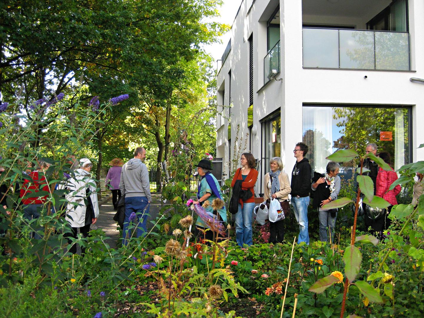 Personen stehen in einer Schlange im grünen Garten vor einem Gebäude