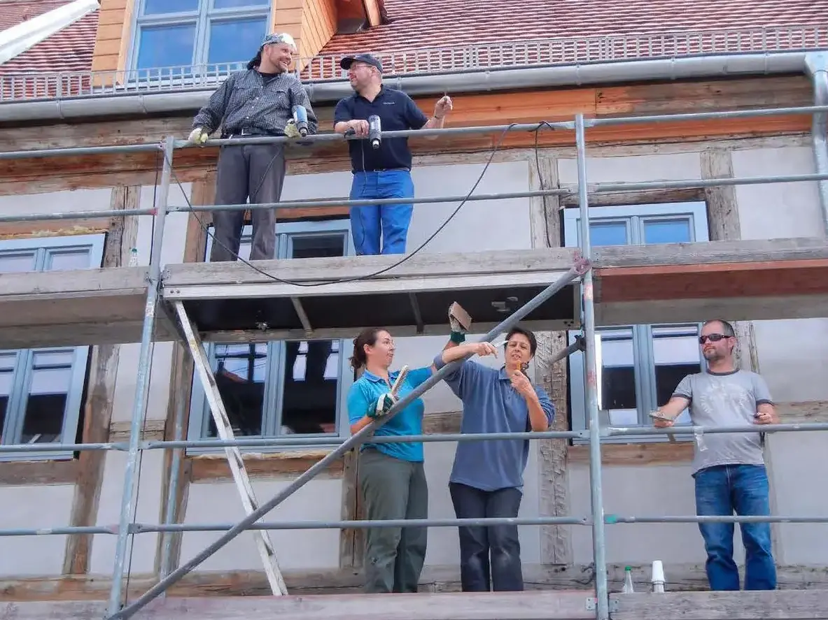 Mehrere Personen stehen auf einem Baugerüst und blicken zur Kamera