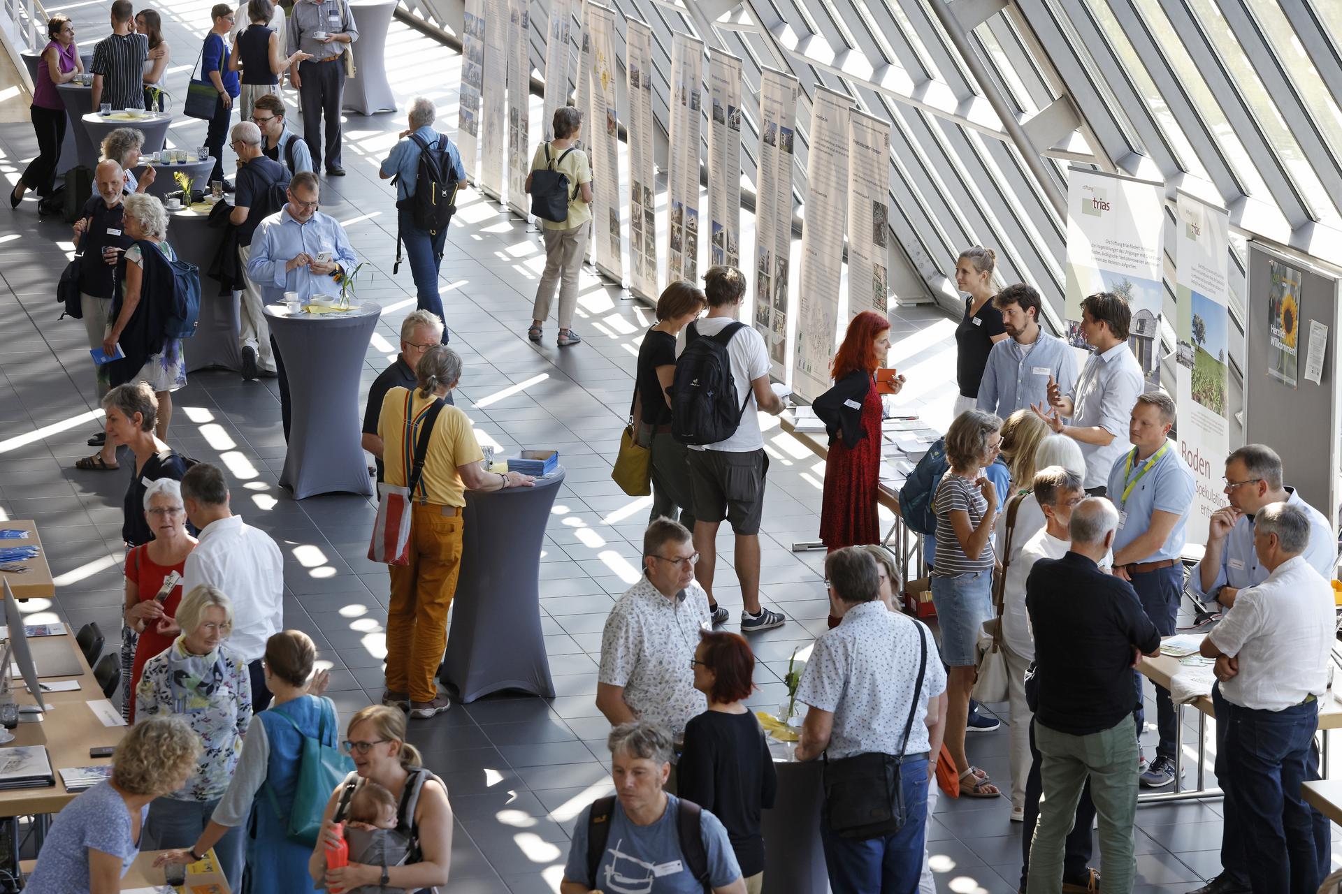 Das helle, verglaste Foyer des Wissenschaftsparks Gelsenkirchen gefüllt mit Infoständen und vielen Menschen