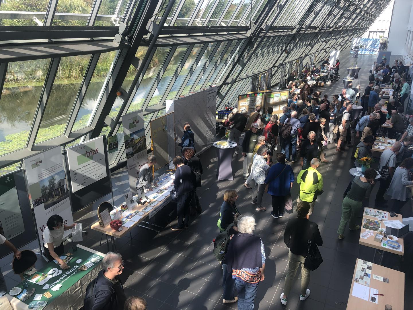 Das helle, verglaste Foyer des Wissenschaftsparks Gelsenkirchen gefüllt mit Infoständen und vielen Menschen