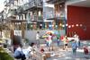 Auf dem Innenhof eines modernen Mehrfamilien-Hauses spielen Kinder und Erwachsene.